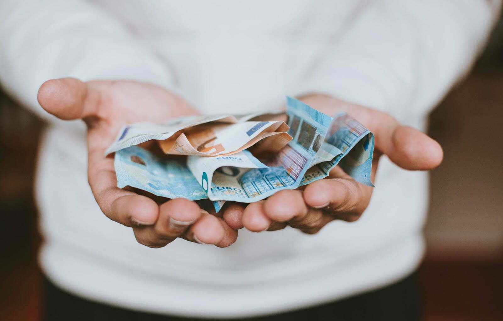 Holding out two handfuls of cash money