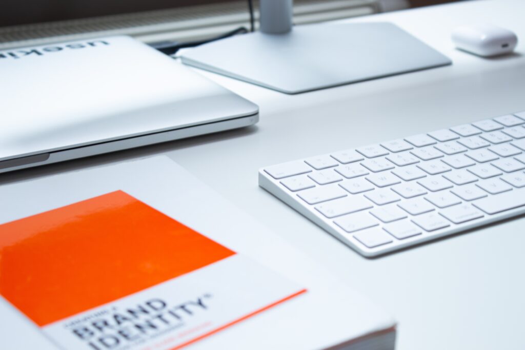 Keyboard on a white desk with a book called Brand Identity next to it